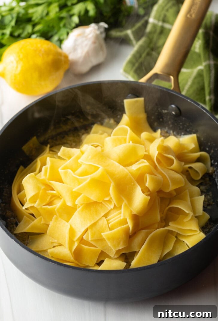 Irresistible Garlic Butter Noodles 7 Black skillet with cooked buttery pasta.