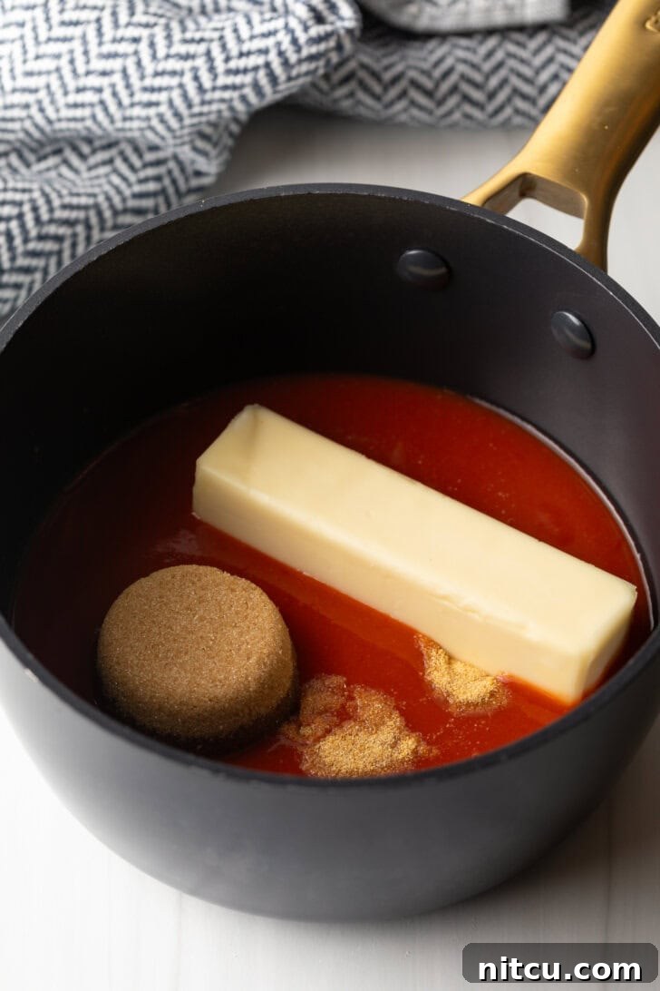 The Best Homemade Buffalo Wing Sauce 5 Black sauce pot with Frank's RedHot, stick of butter, and scoop of brown sugar.