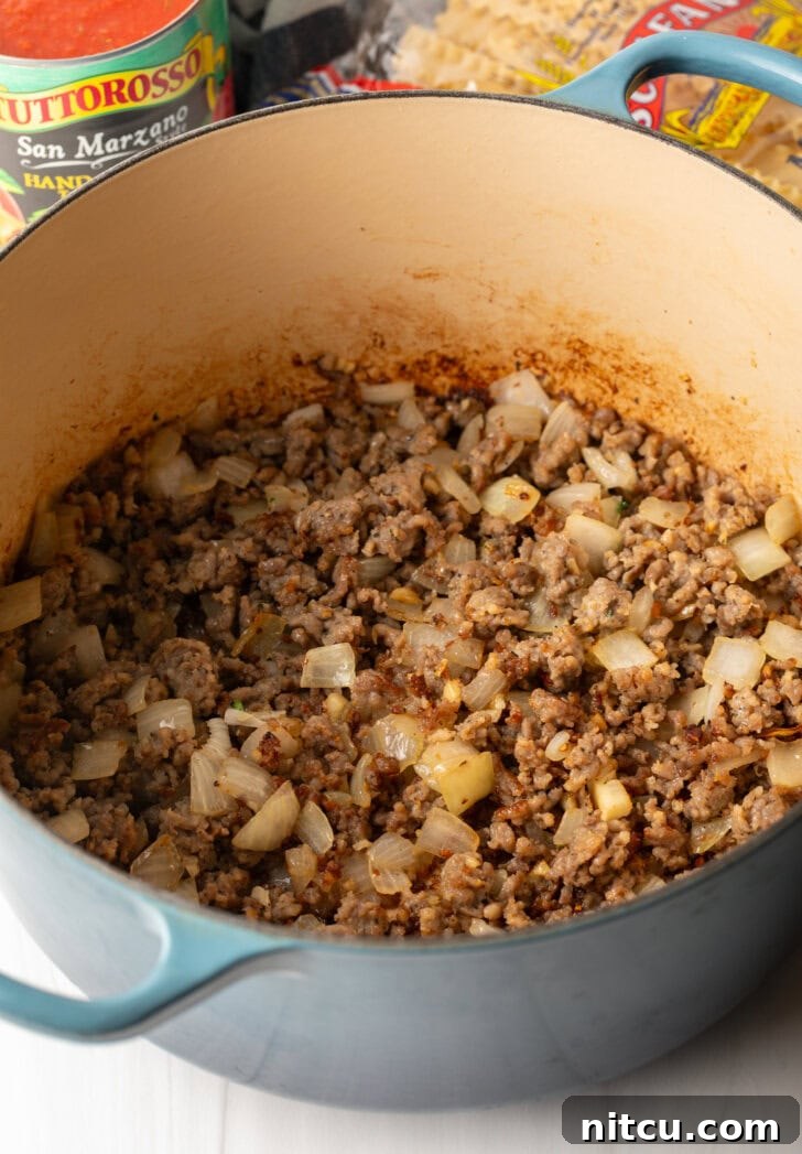 One-Pot Lasagna Delight 6 A large pot on the stove, containing perfectly browned ground sausage mixed with softened onions, preparing the flavor base for the soup.