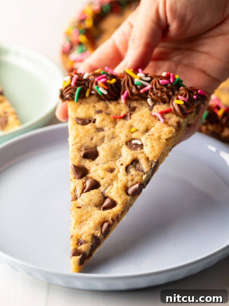 Ultimate Chocolate Chip Cookie Cake 13 One triangle slice of homemade cookie cake on a pastel blue plate.