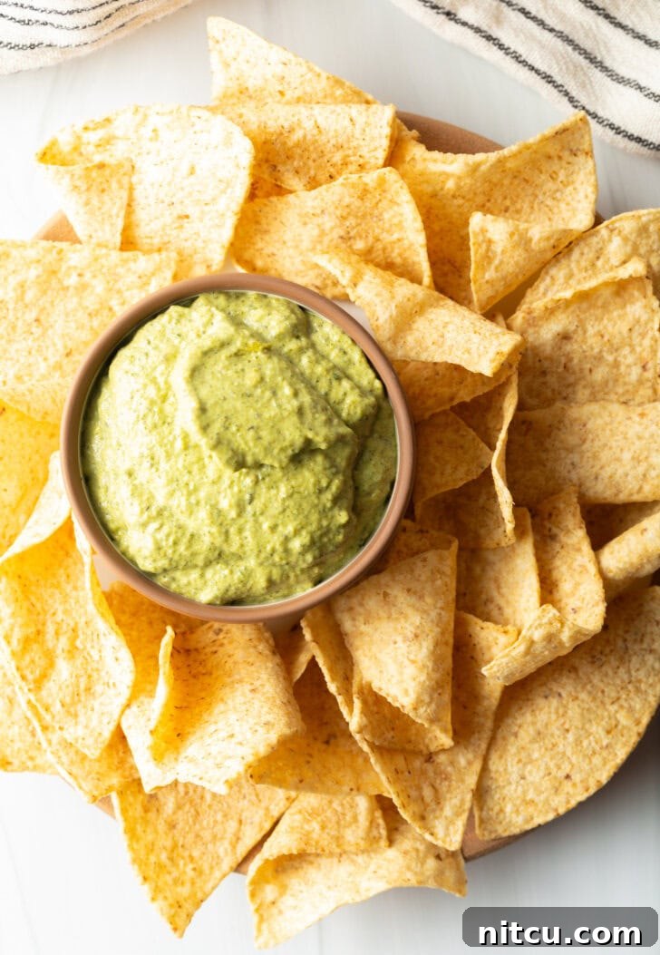 Top down small bowl of poblano cream sauce surrounded by tortilla chips.