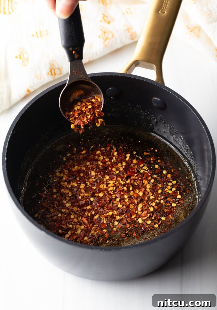 Spoon showing a spoonful of hot honey from a black cooking pot to camera.