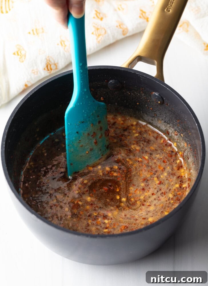 Blue spatula stirring mixture in a black sauce pot.