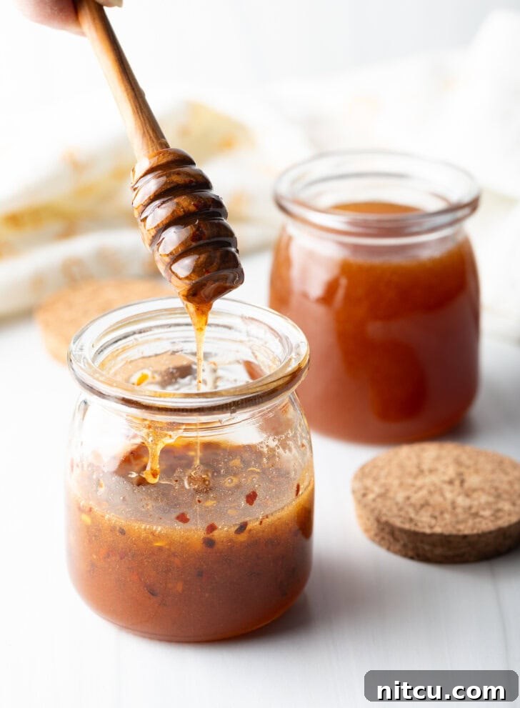 Two jars of honey honey. A honey spoon is showing a serving from the first jar.