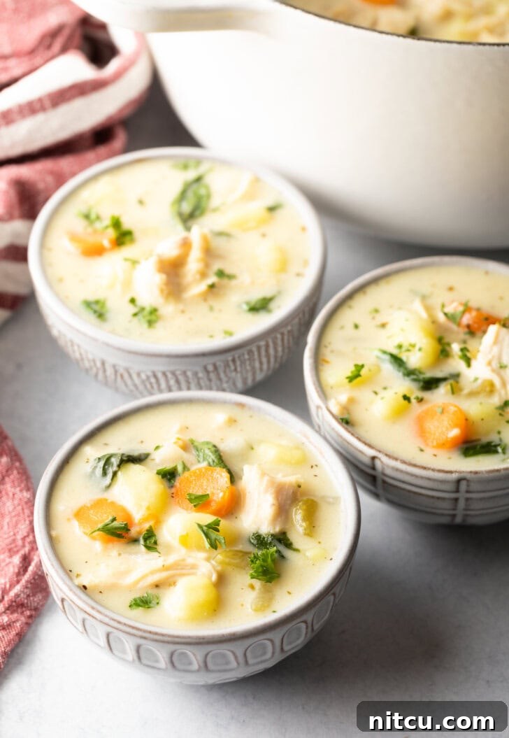 Three perfectly presented white bowls of homemade Olive Garden-style chicken gnocchi soup, ready for a comforting meal.