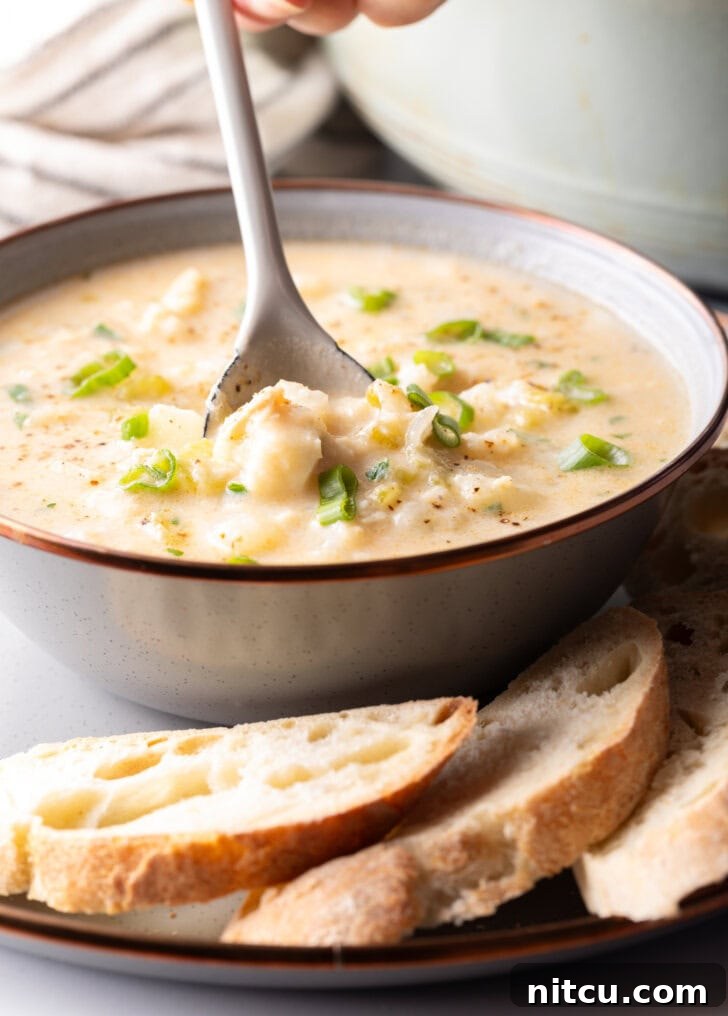 Hearty Seafood Chowder 4 Side view of the chowder in a bowl, with a spoon going in for a scoop.