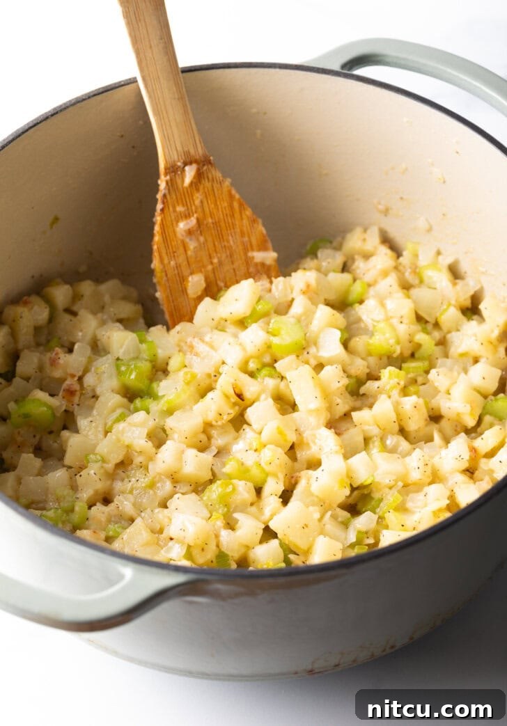 Hearty Seafood Chowder 5 Cooking chopped onion, celery, and potato in a large pot with a wooden spatula.