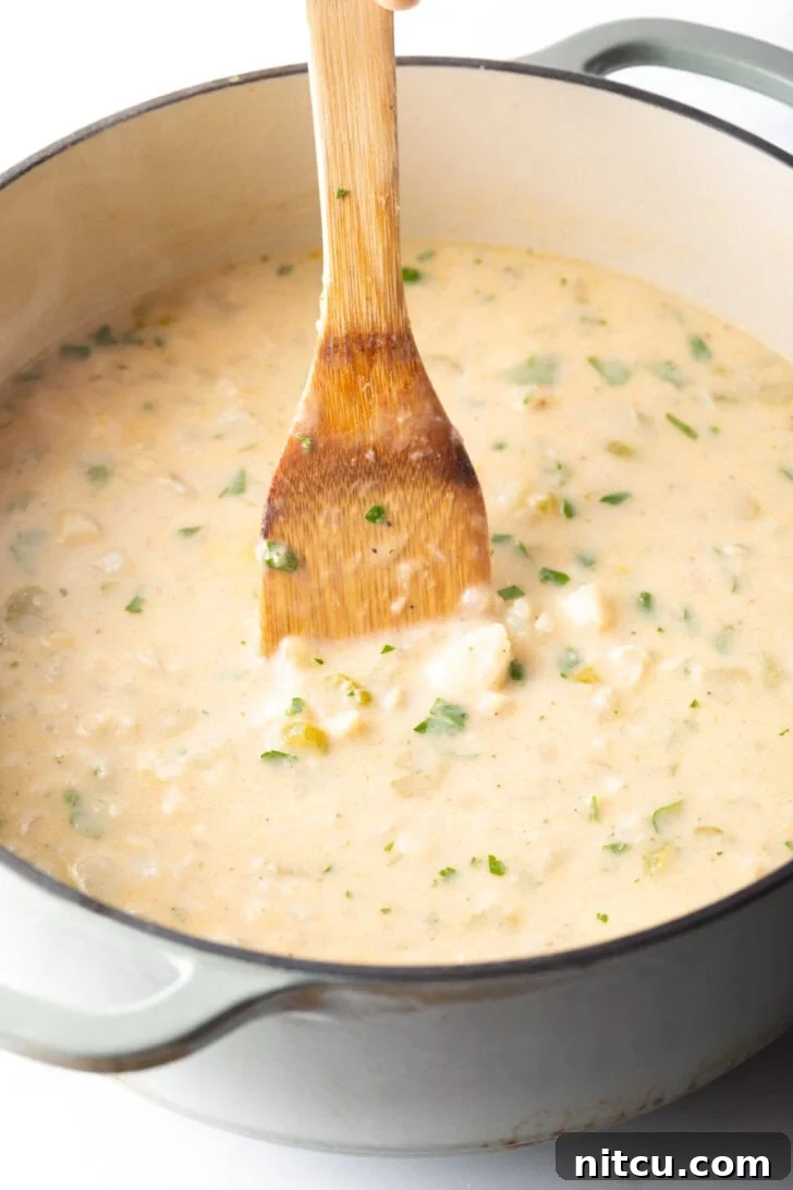 Hearty Seafood Chowder 8 Wooden spatula stirring the fish chowder in a large cooking pot.