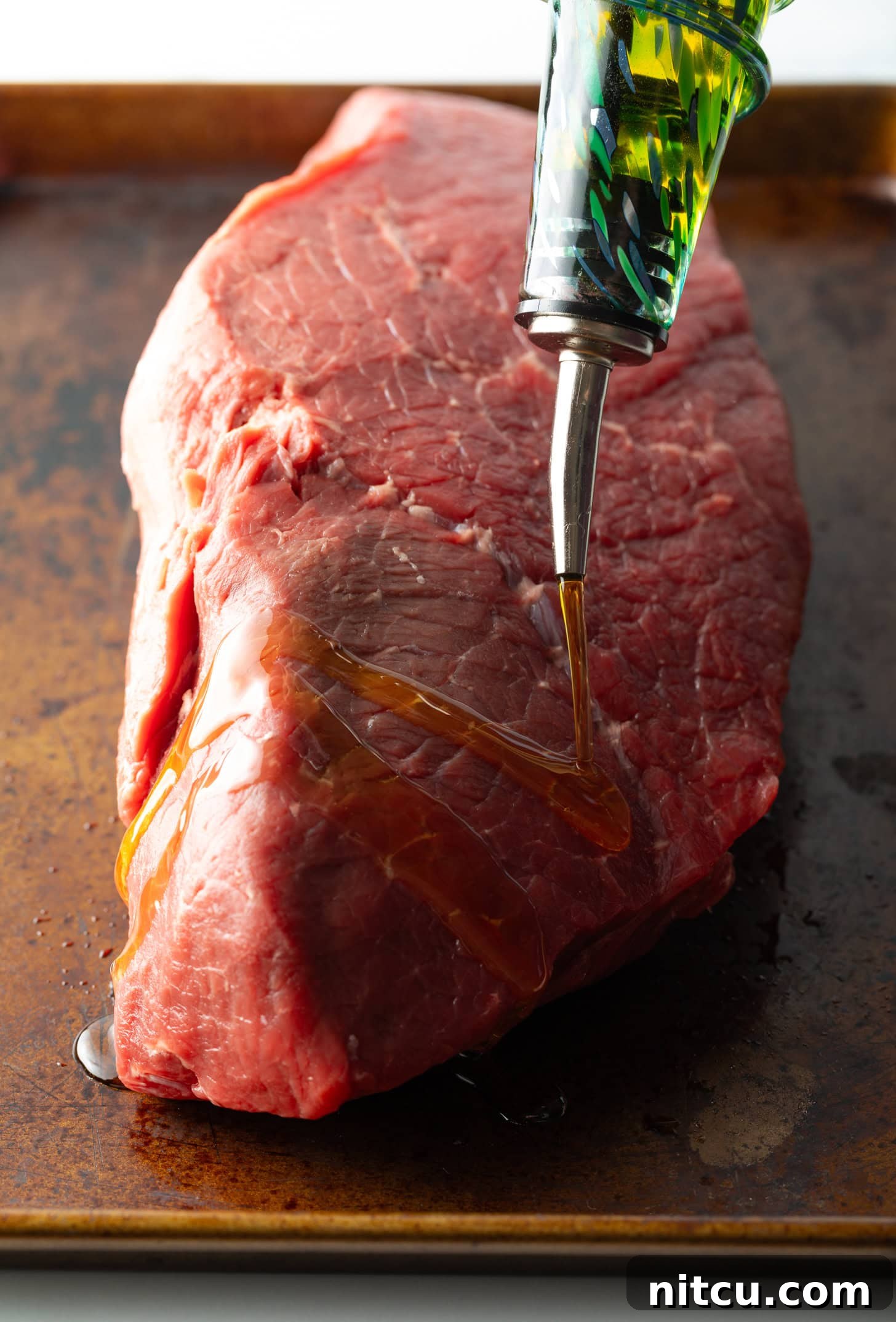 Savory Top Round Roast 5 Coating a large piece of raw been with olive oil.