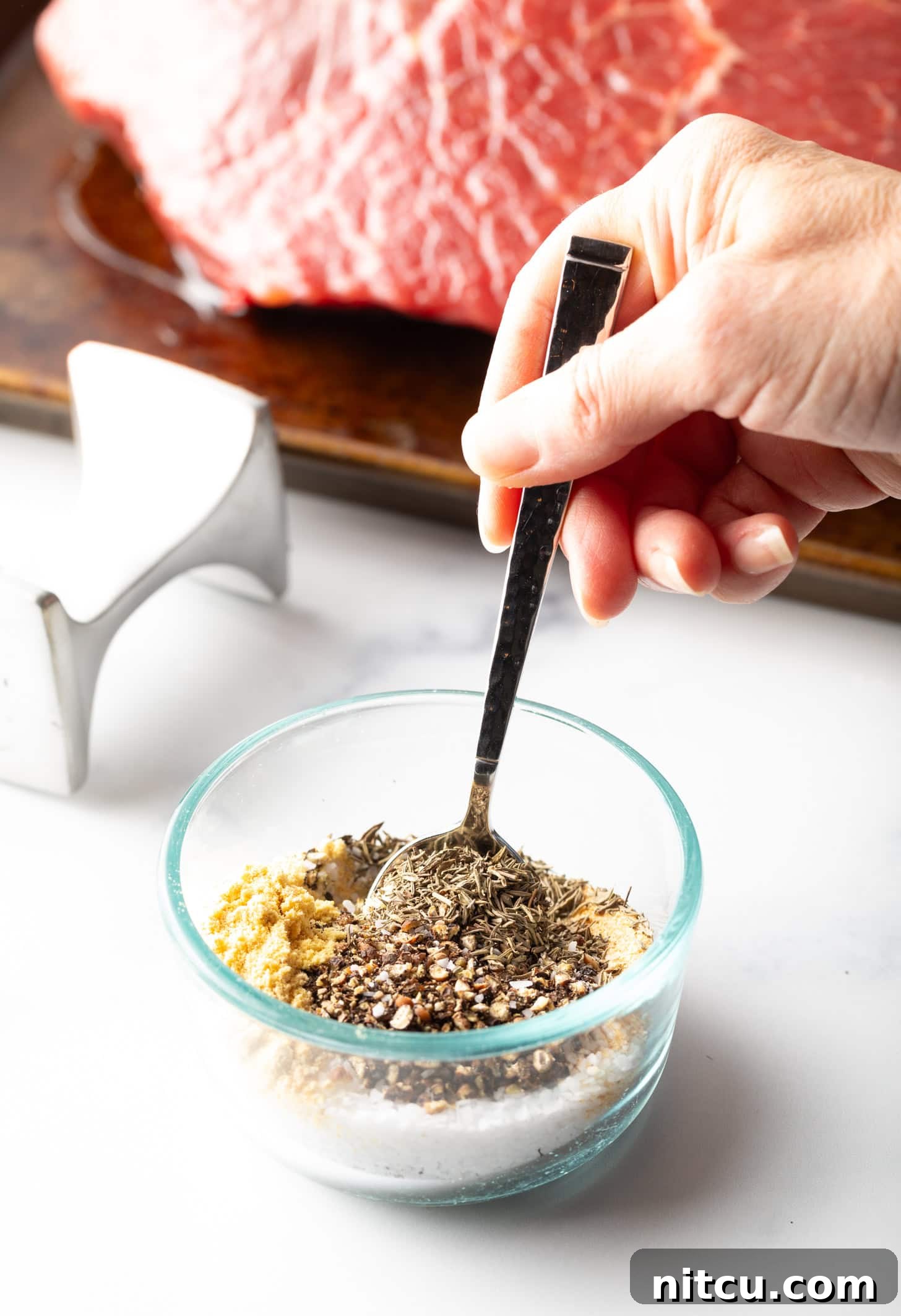 Savory Top Round Roast 7 Hand stirring seasoning mix together in a small glass bowl.
