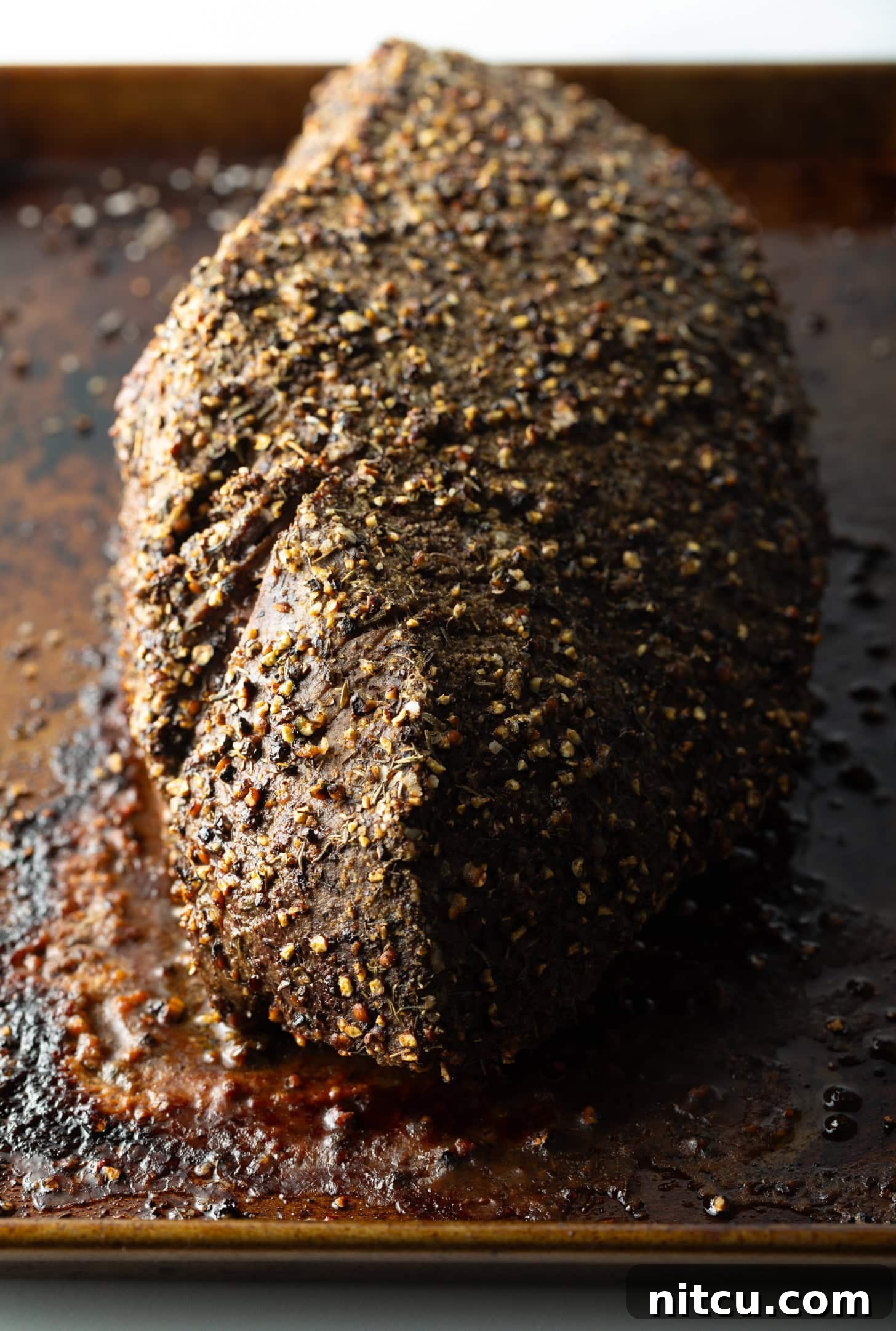 Savory Top Round Roast 9 Top down view cooked beef round roast on a metal baking pan.