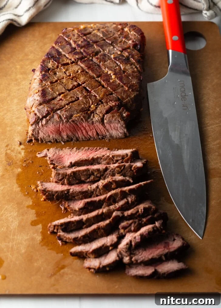Signature London Broil Marinade 11 Top down view of london broil thinly sliced on a cutting board with large knife