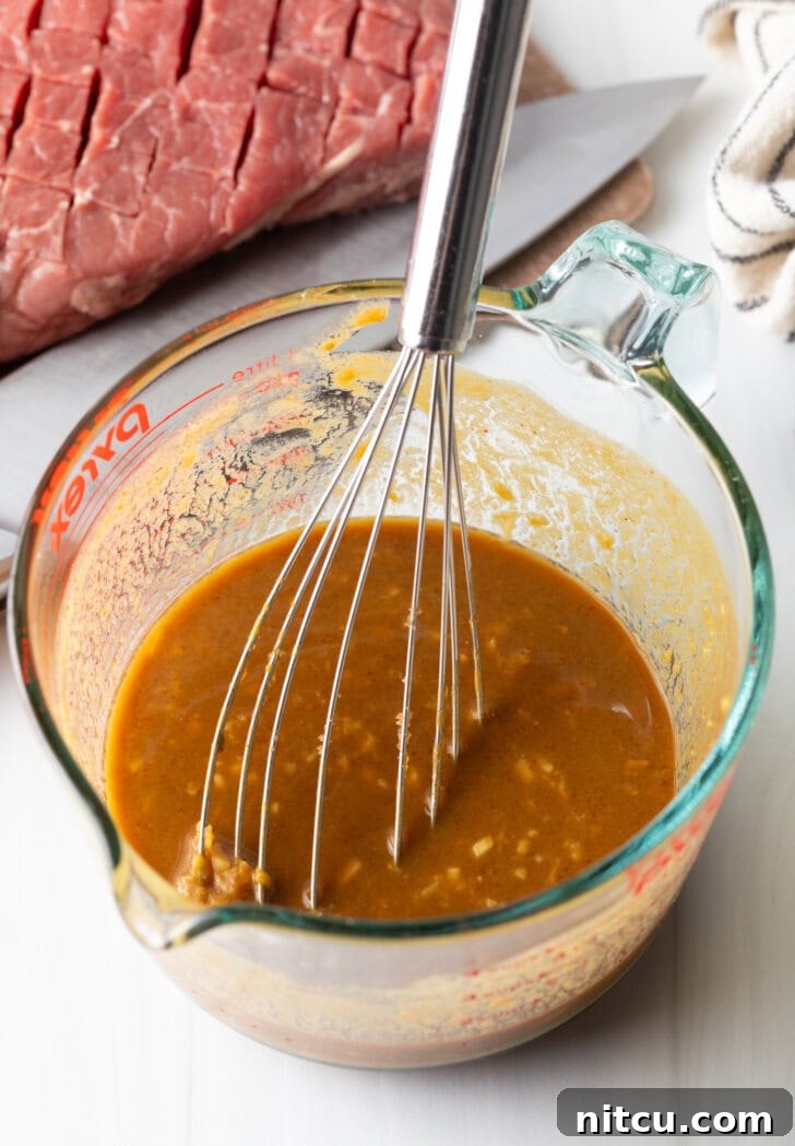 Signature London Broil Marinade 7 Whisk in a glass measuring cup with marinade.