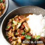 Bowl of chicken sausage gumbo with a scoop of white rice.
