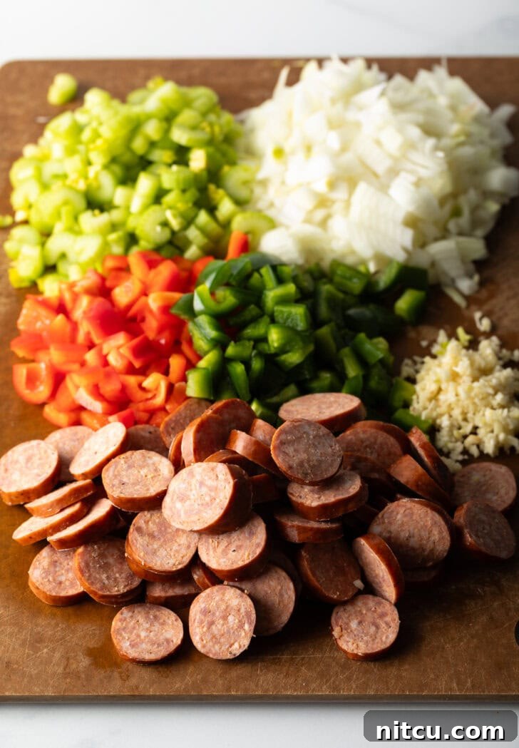 Chopped recipe ingredients on a cutting board: Sausage, red peppers, green peppers, garlic, onion, and celery.