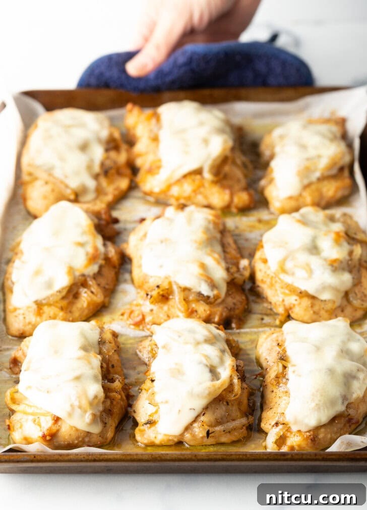 9 chicken thighs on a baking sheet topped with melted provolone cheese.