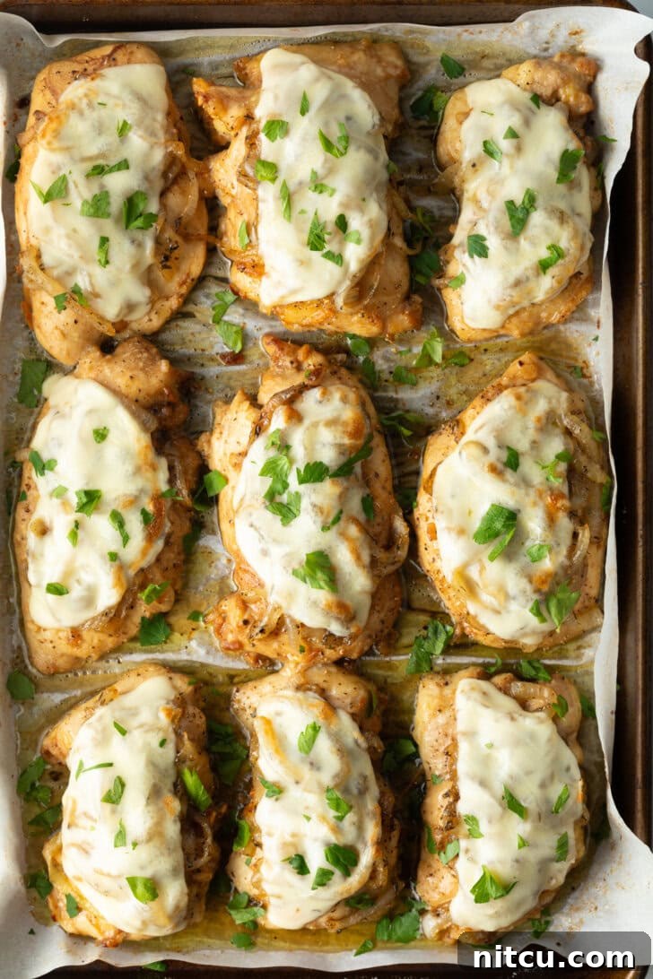 9 chicken thighs on a baking sheet topped with melted provolone cheese.