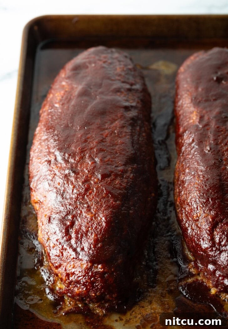 Pitmaster's Meatloaf 11 A top-down shot of two perfectly cooked and glazed meatloaves resting after being removed from the smoker, showcasing their rich color and inviting aroma.