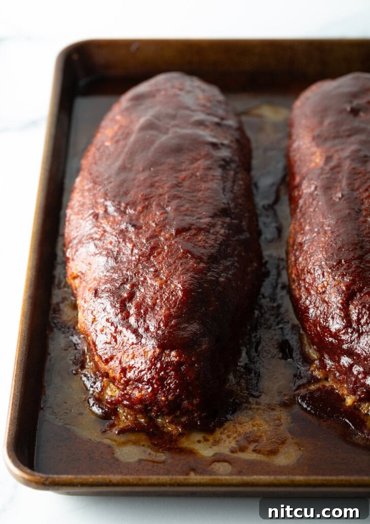 Pitmaster's Meatloaf 4 A top-down view showcasing two perfectly smoked meatloaves fresh out of the smoker, glistening with a savory glaze.