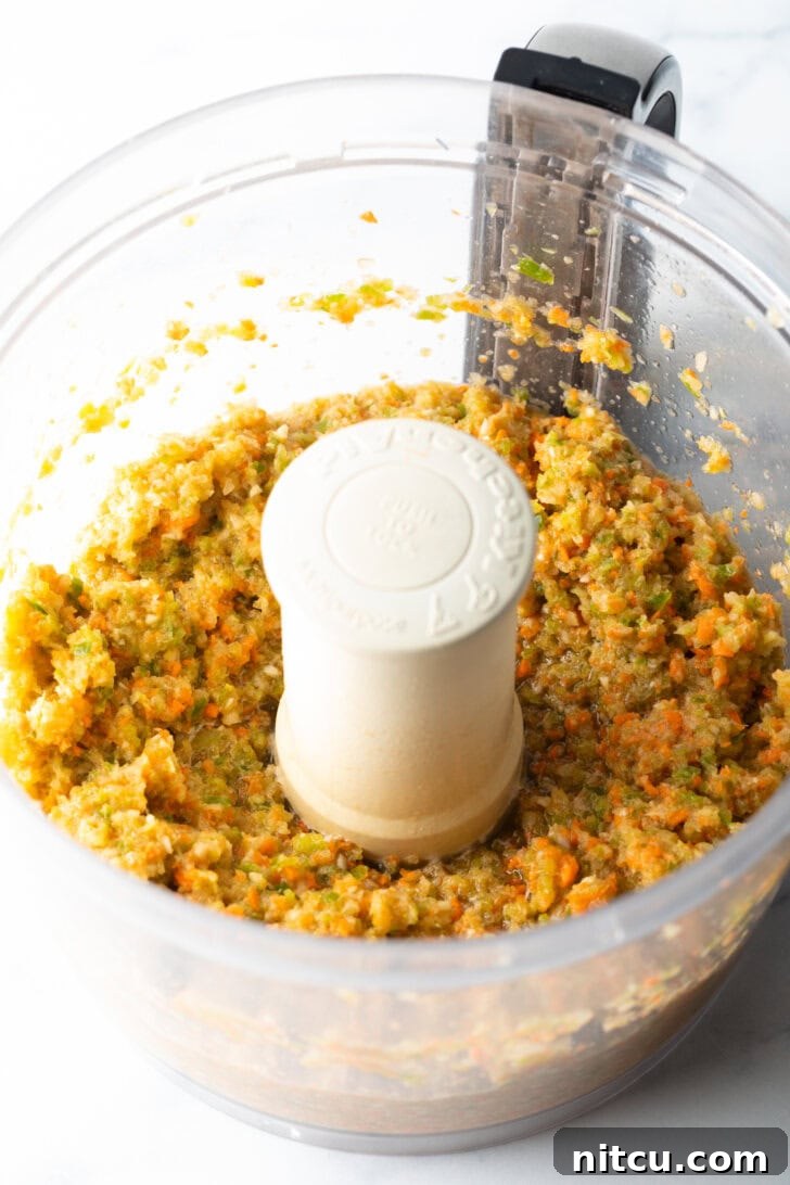 Pitmaster's Meatloaf 6 A large mixing bowl filled with ground beef, minced vegetables, and various spices, poised for the hand-mixing stage of the meatloaf preparation.