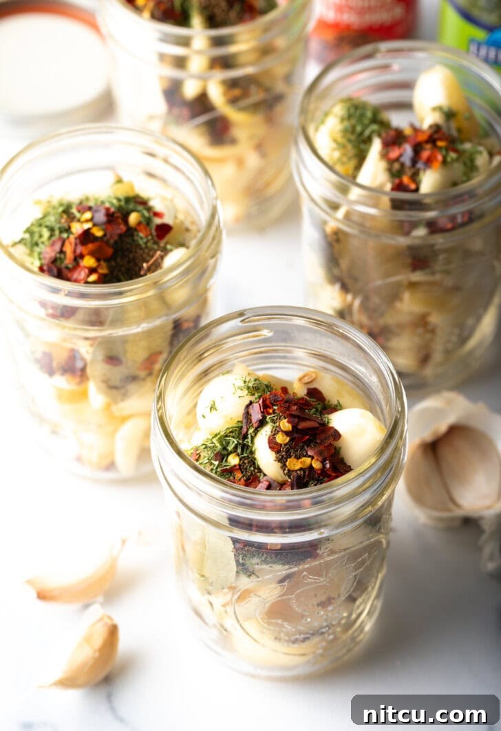 Zesty Pickled Garlic 6 Top down open glass jar stuffed with preserved garlic and herbs.