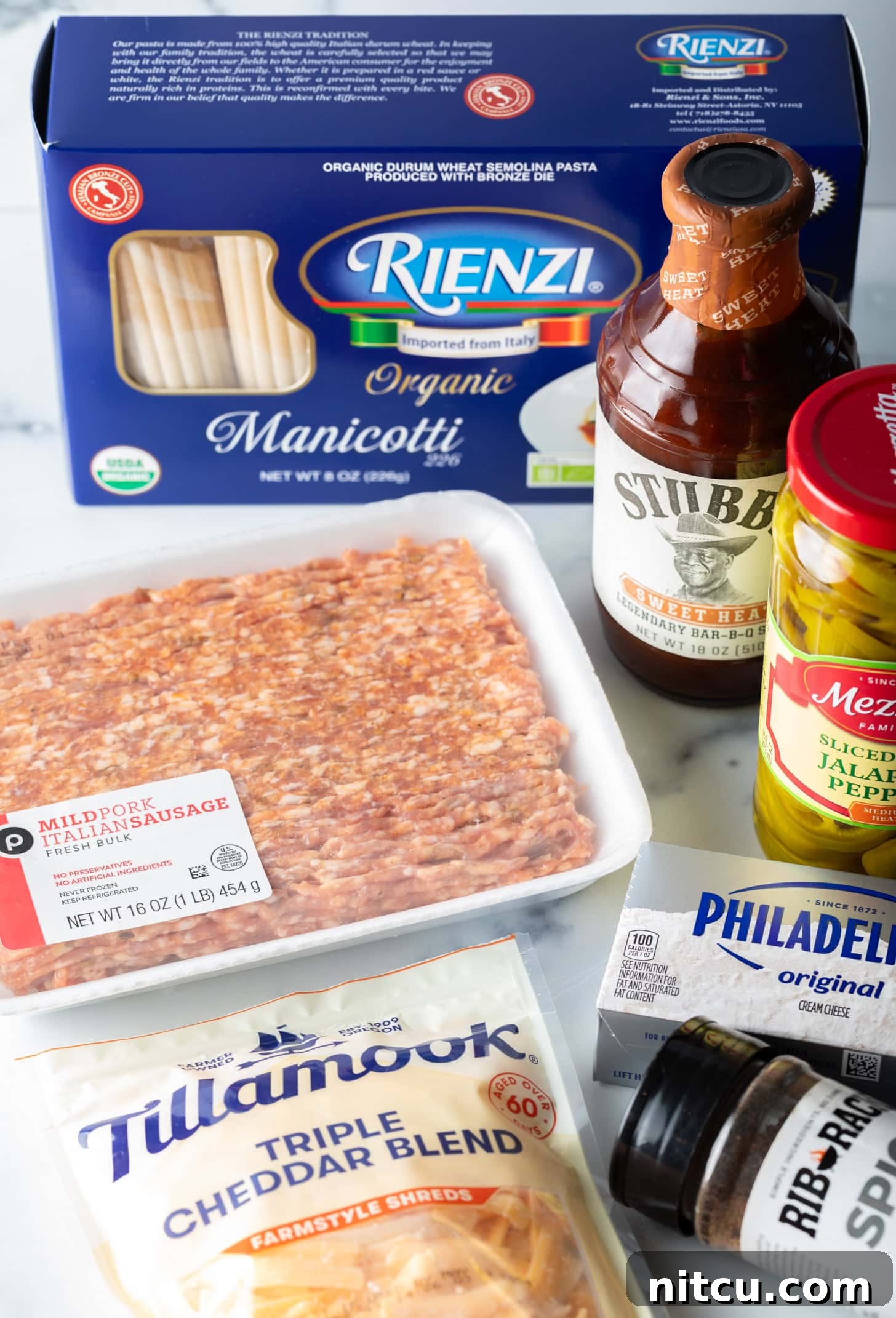 Smoked & Loaded Shells 5 Recipe ingredients: Package of ground meat, bottle of bbq sauce, jar of pepperoncinis, box of manicotti noodles, packages of cream cheese and shredded cheddar cheese.