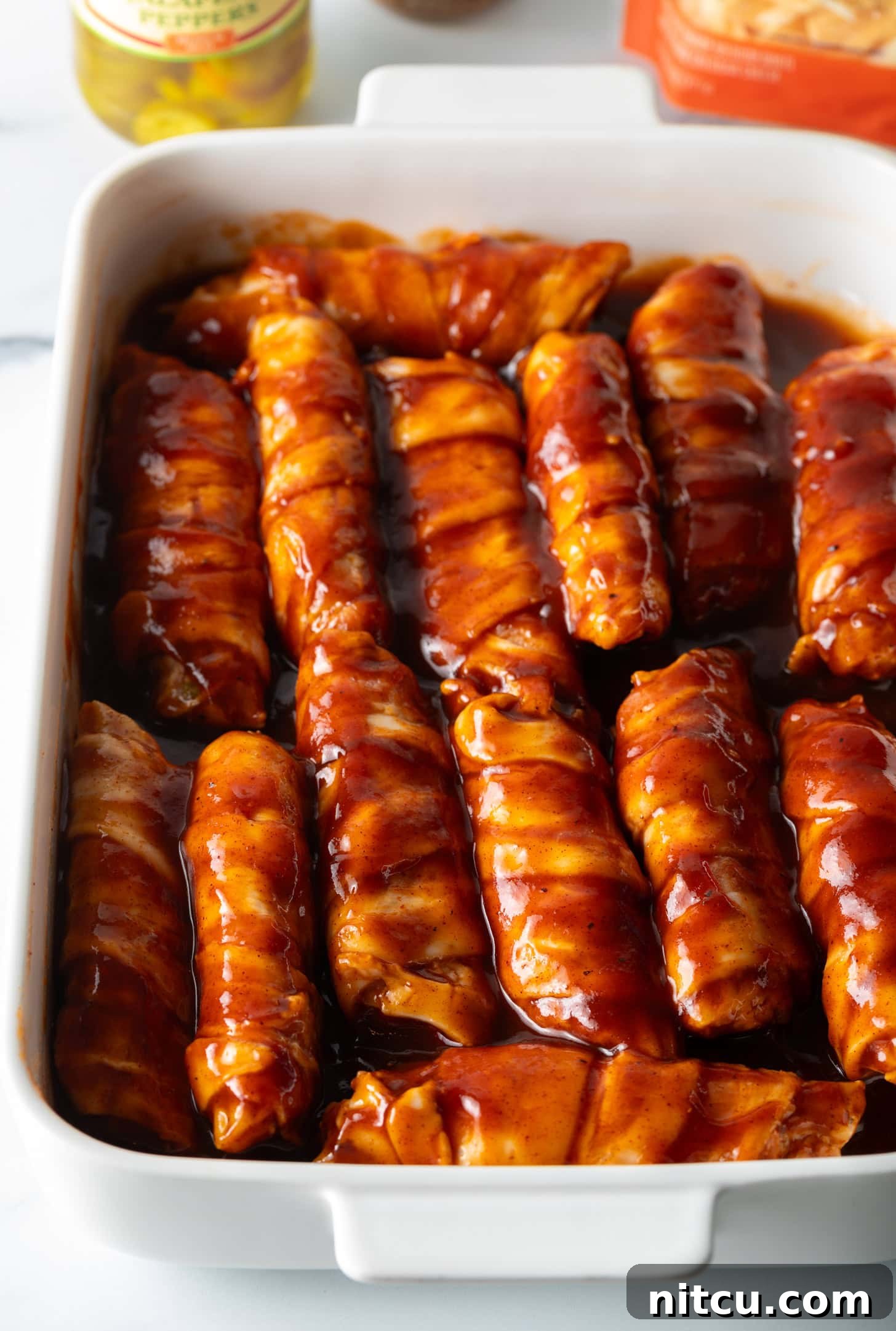 Smoked & Loaded Shells 9 White baking dish filled with raw stuffs shells, all coated in bbq sauce.