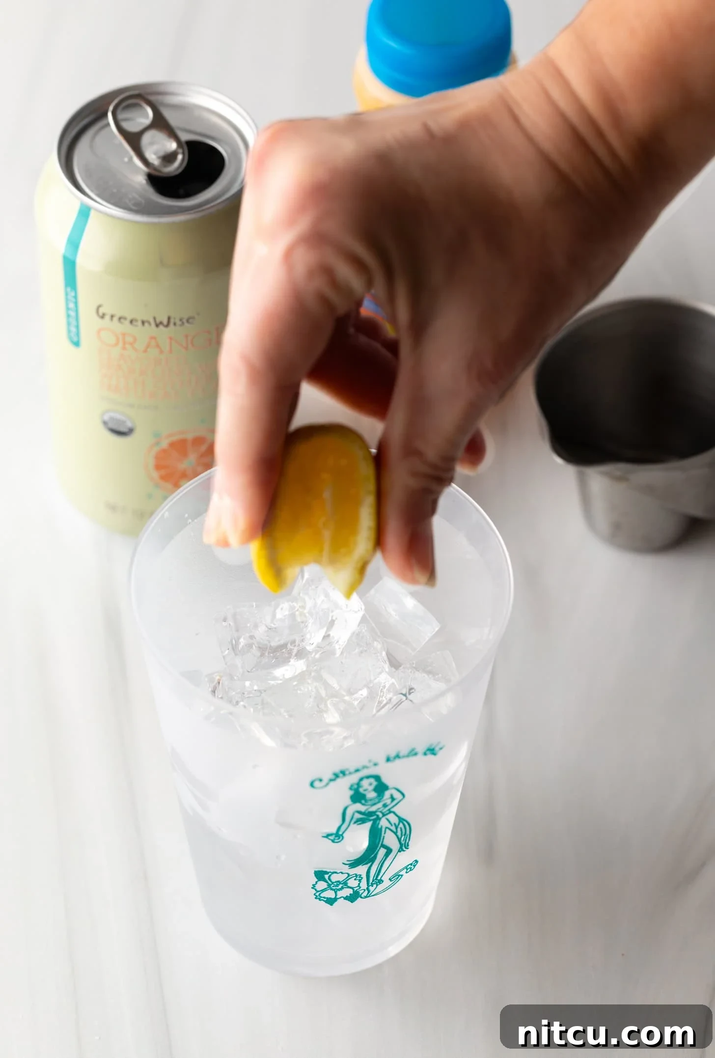 Sunny D Zest Seltzer 6 Hand squeezing orange juice into a glass filled with ice.