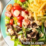 Big Mac Burger Bowl 10 A hearty Big Mac burger salad with shredded lettuce, ground beef, halved grape tomatoes, shredded cheese, pickles, and sliced green onion, all topped with a drizzle of Thousand island dressing.
