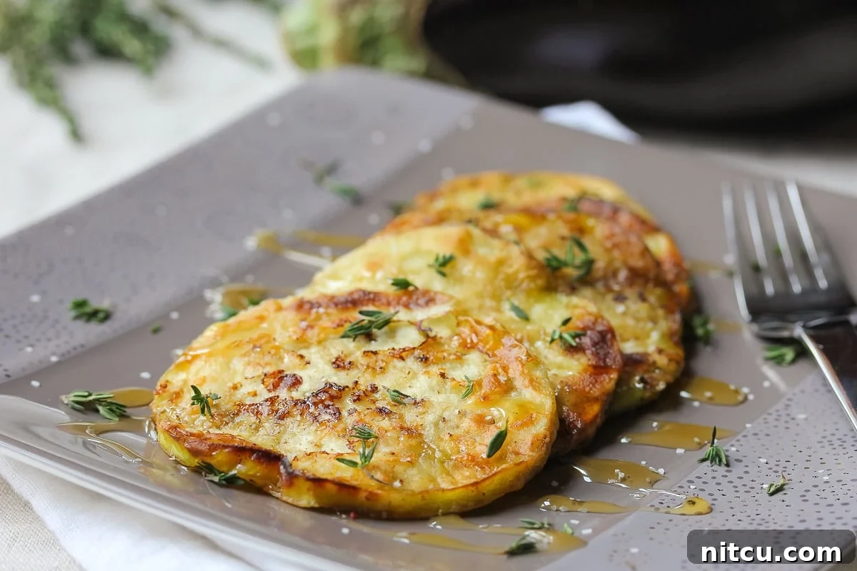 Close-up of golden brown sautéed eggplant slices being drizzled with honey, highlighting the perfect caramelization and glossy finish.