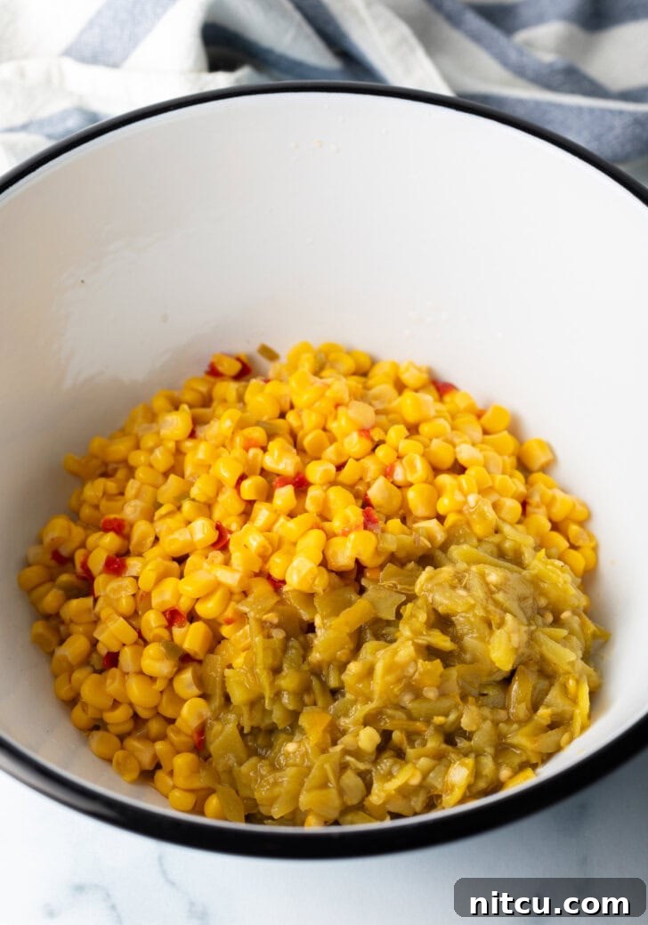 Creamy Street Corn Dip 4 Close-up of a white bowl filled with Mexicorn and finely chopped pickled jalapeño peppers, showcasing the key ingredients.