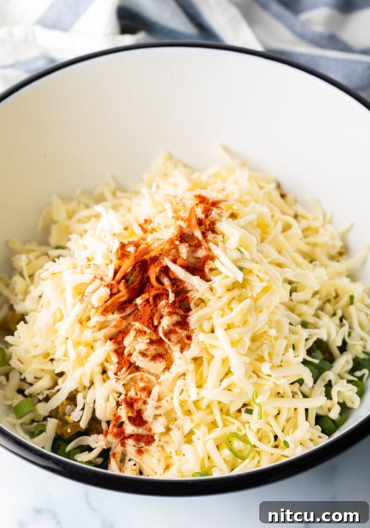 Creamy Street Corn Dip 5 Various spices and shredded cheese being added to a bowl containing the remaining dip ingredients, ready for mixing.