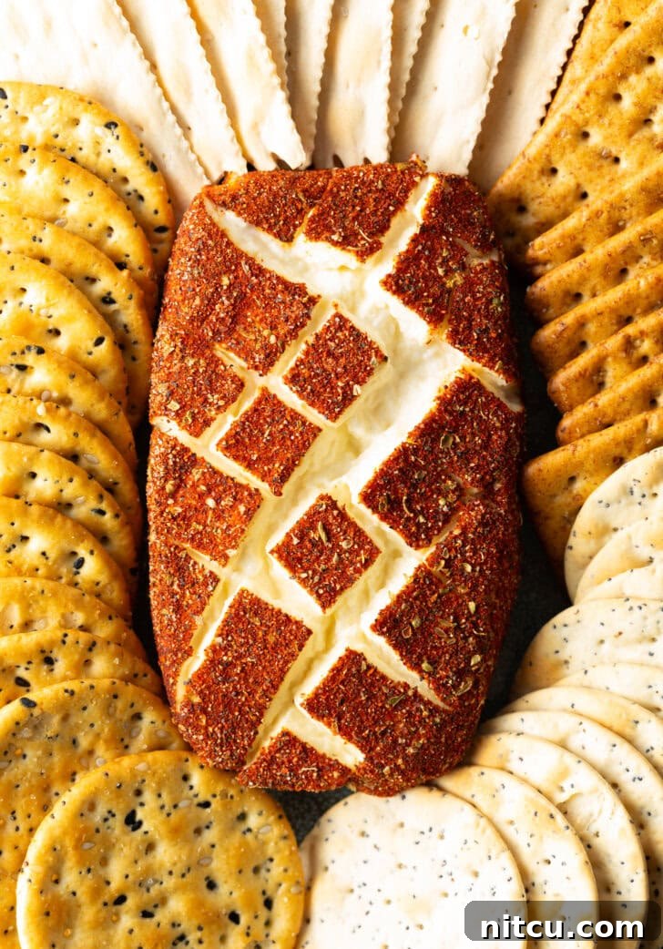 Top down view of a block of spice-coated smoked cream cheese surrounded by various crackers.
