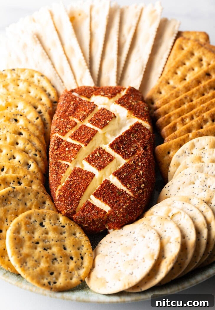 Top down view of a block of spice-coated smoked cream cheese surrounded by various crackers.