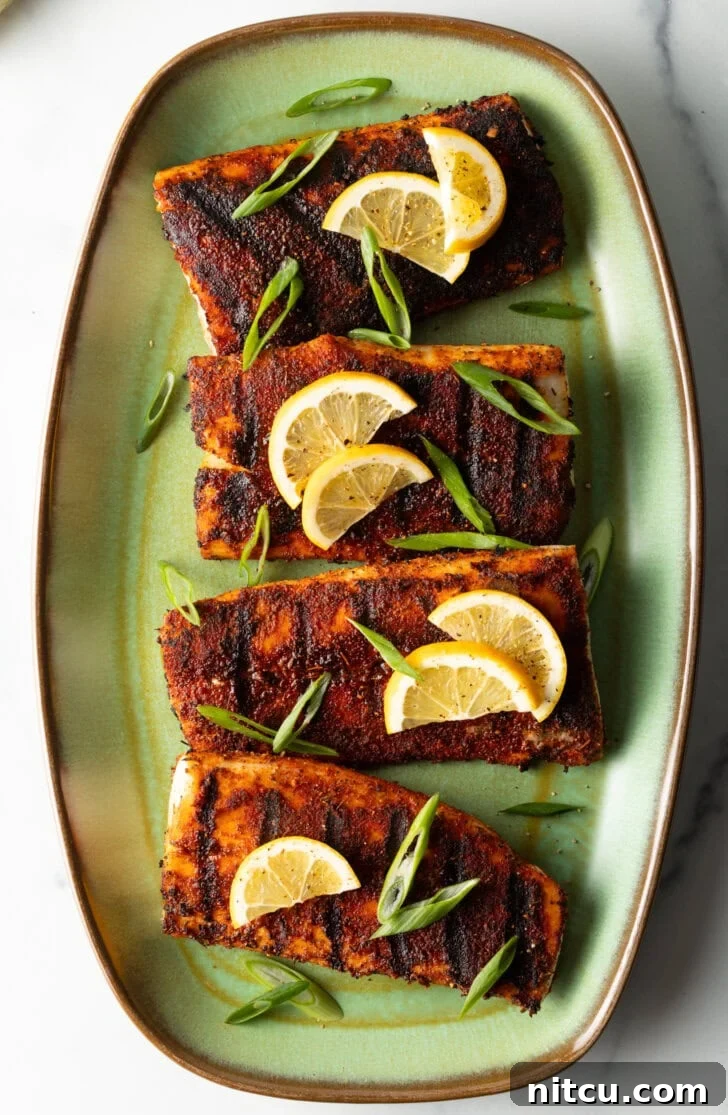Fiery Blackened Mahi Delight 3 Top down view of 4 pieces of blackened and grilled fish, all topped with slices of lemon and green onions.
