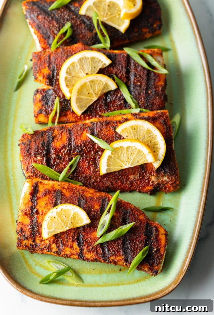 Fiery Blackened Mahi Delight 9 Top down view of 4 pieces of blackened and grilled fish, all topped with slices of lemon and green onions.