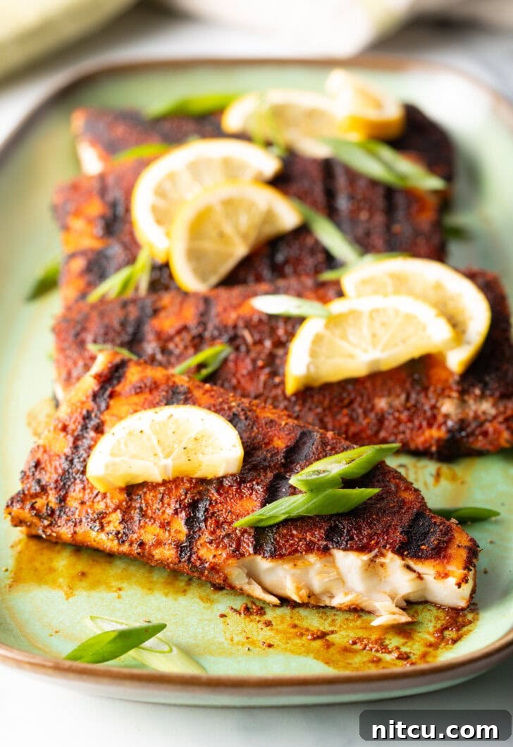 Fiery Blackened Mahi Delight 10 4 fillets of grilled mahi mahi topped with a slice of lemon and green onions. A bite has been removed from the fish to show the white flaky inside of the meat.