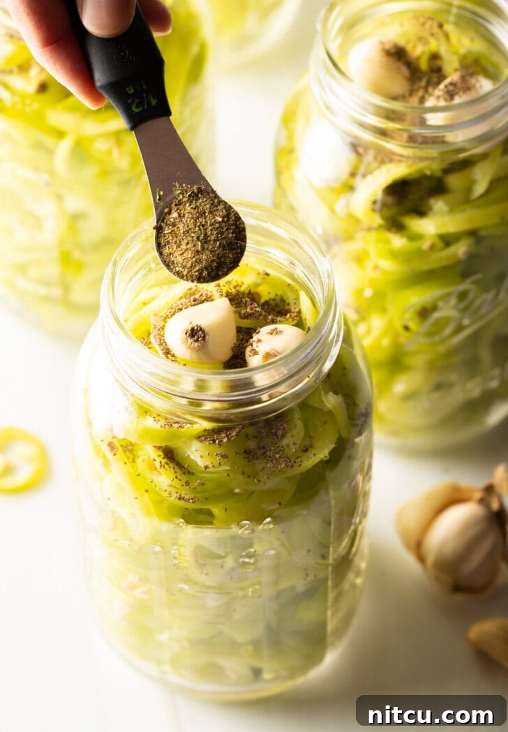 Sweet and Tangy Pickled Banana Peppers 7 Adding spices to glass jars filled with pepper slices and garlic cloves.