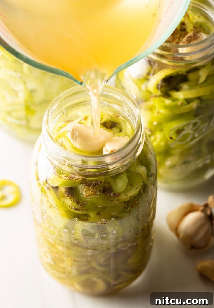 Sweet and Tangy Pickled Banana Peppers 8 Pouring pickling brine into a jar of sliced peppers.