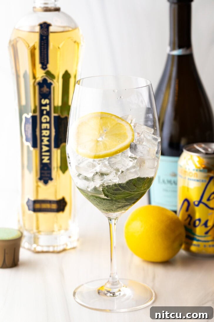 St-Germain Garden Spritz 6 Wine glass filled with mint leaves, ice, and slice of lemon.