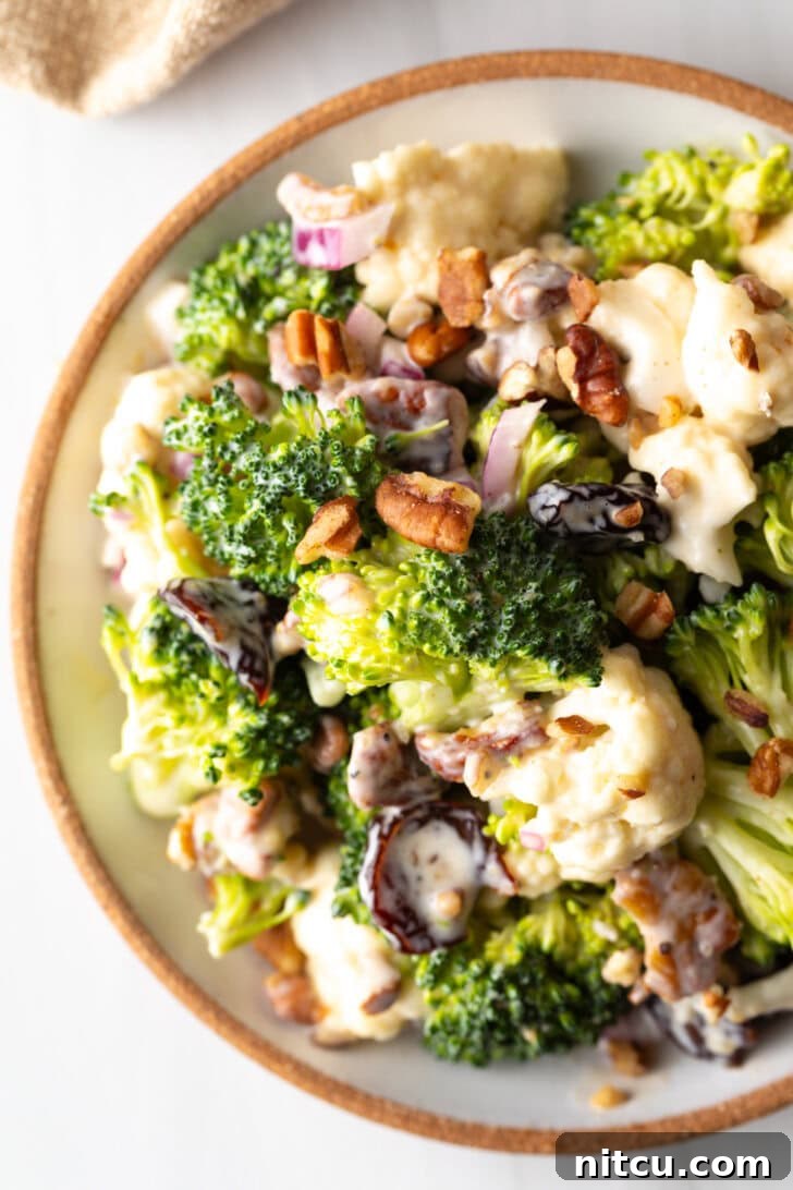 Vibrant Broccoli Cauliflower Salad 4 Top down view of a large bowl filled with vibrant broccoli and cauliflower salad, showcasing its fresh ingredients and creamy dressing.