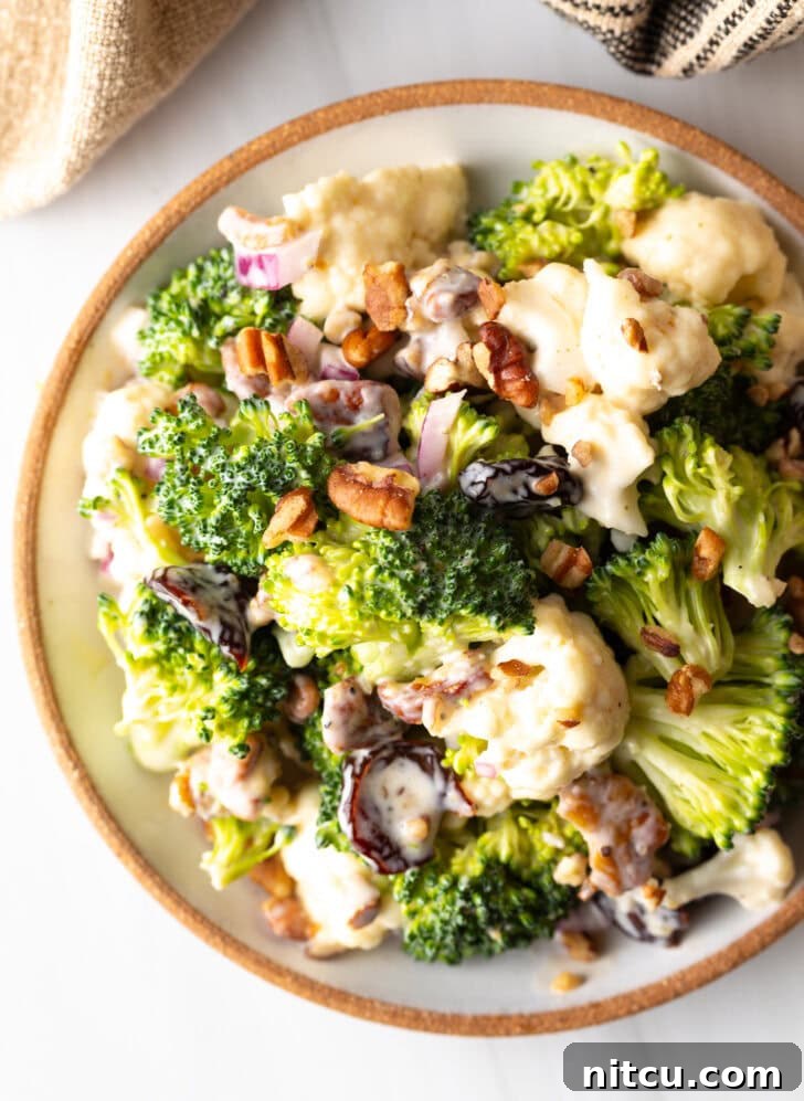 Vibrant Broccoli Cauliflower Salad 9 Top down view of a large bowl filled with appetizing broccoli cauliflower salad, showcasing its fresh ingredients and inviting texture.