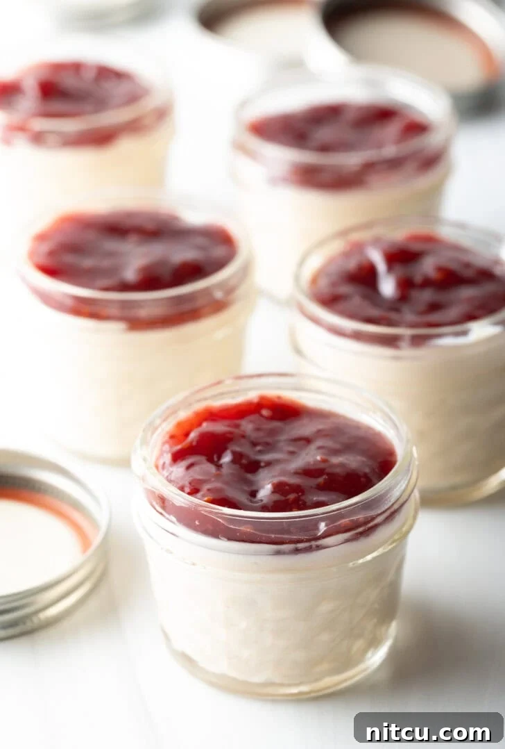 High-Protein Yogurt Pudding 2 5 small glass jars of protein pudding topped with raspberry jam.
