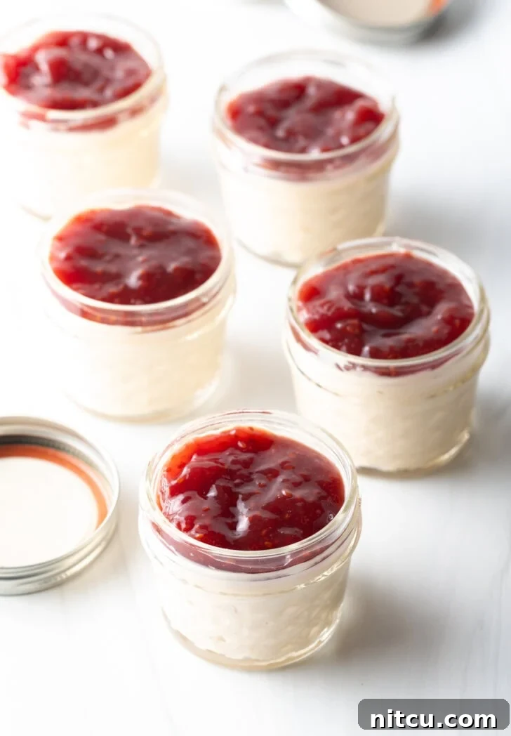 High-Protein Yogurt Pudding 7 5 small glass jars of protein pudding topped with raspberry jam.