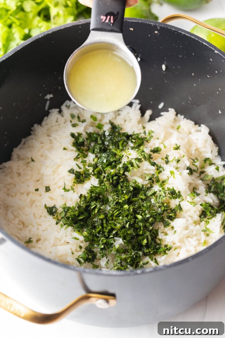 Homemade Chipotle Cilantro Lime Rice 7 Adding lime juice from a measuring spoon over a pot with rice and chopped cilantro.