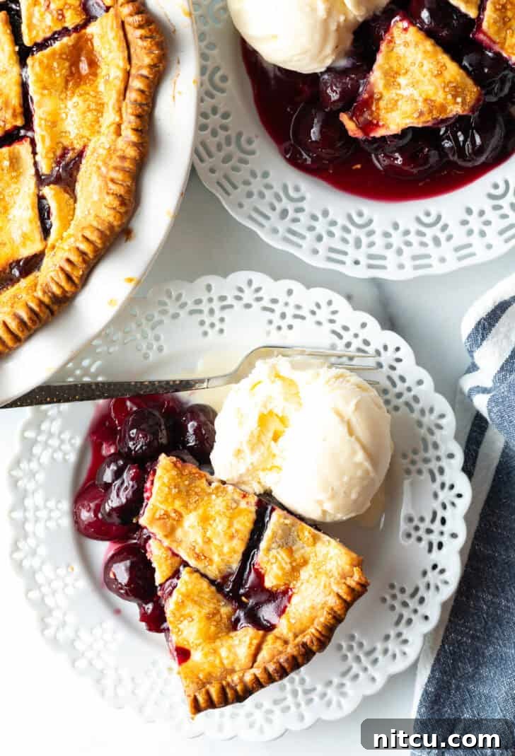 Sweet Cherry Pie Delight 13 A top-down view of a perfect slice of homemade cherry pie with scratch-made filling, resting on a white plate, accompanied by a melting scoop of vanilla ice cream – an irresistible dessert.