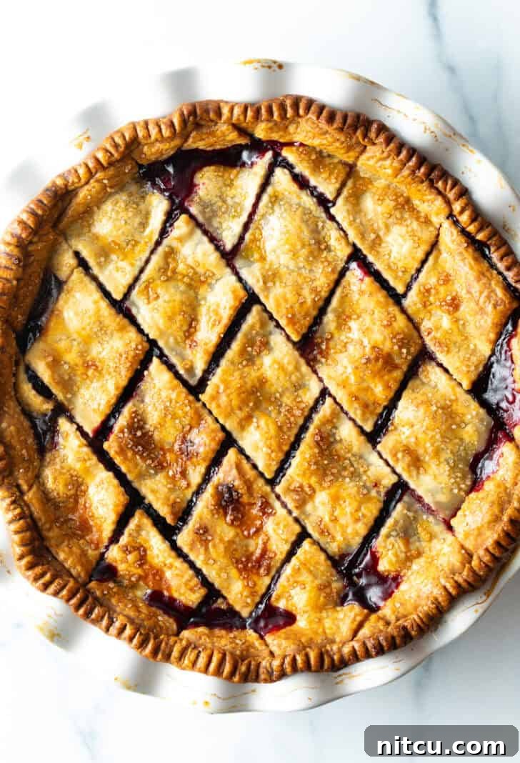 Sweet Cherry Pie Delight 4 A beautifully baked cherry pie, featuring a golden, intricately patterned diamond crust, showcases the rich, homemade cherry pie filling beneath.