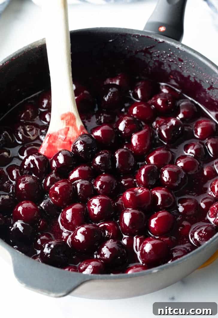 Sweet Cherry Pie Delight 7 Homemade cherry pie filling simmering gently in a large pot, with a wooden spoon stirring the vibrant red mixture, showing the filling in its cooking process.
