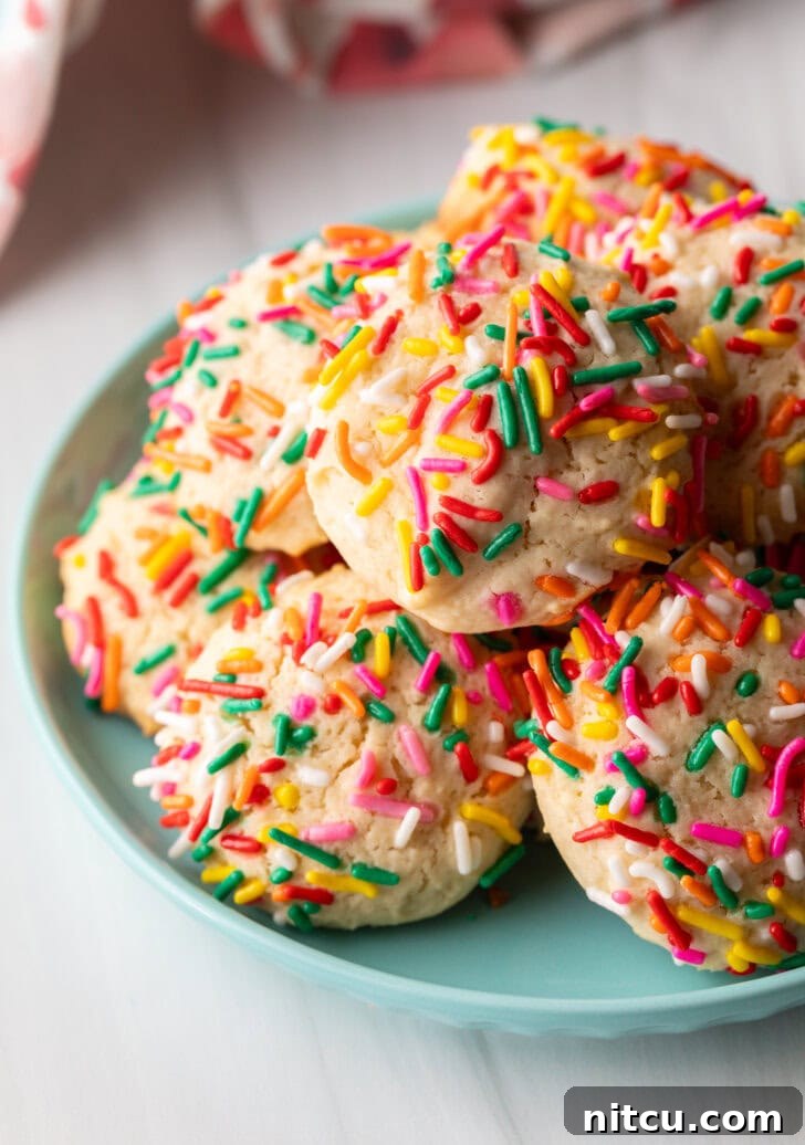 Velvety Cream Cheese Bites 2 Blue plate piled with cookies covered in colorful sprinkles.
