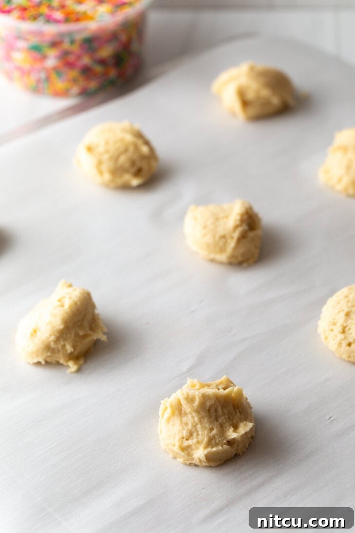 Velvety Cream Cheese Bites 5 Several raw cookie dough balls on a baking sheet.
